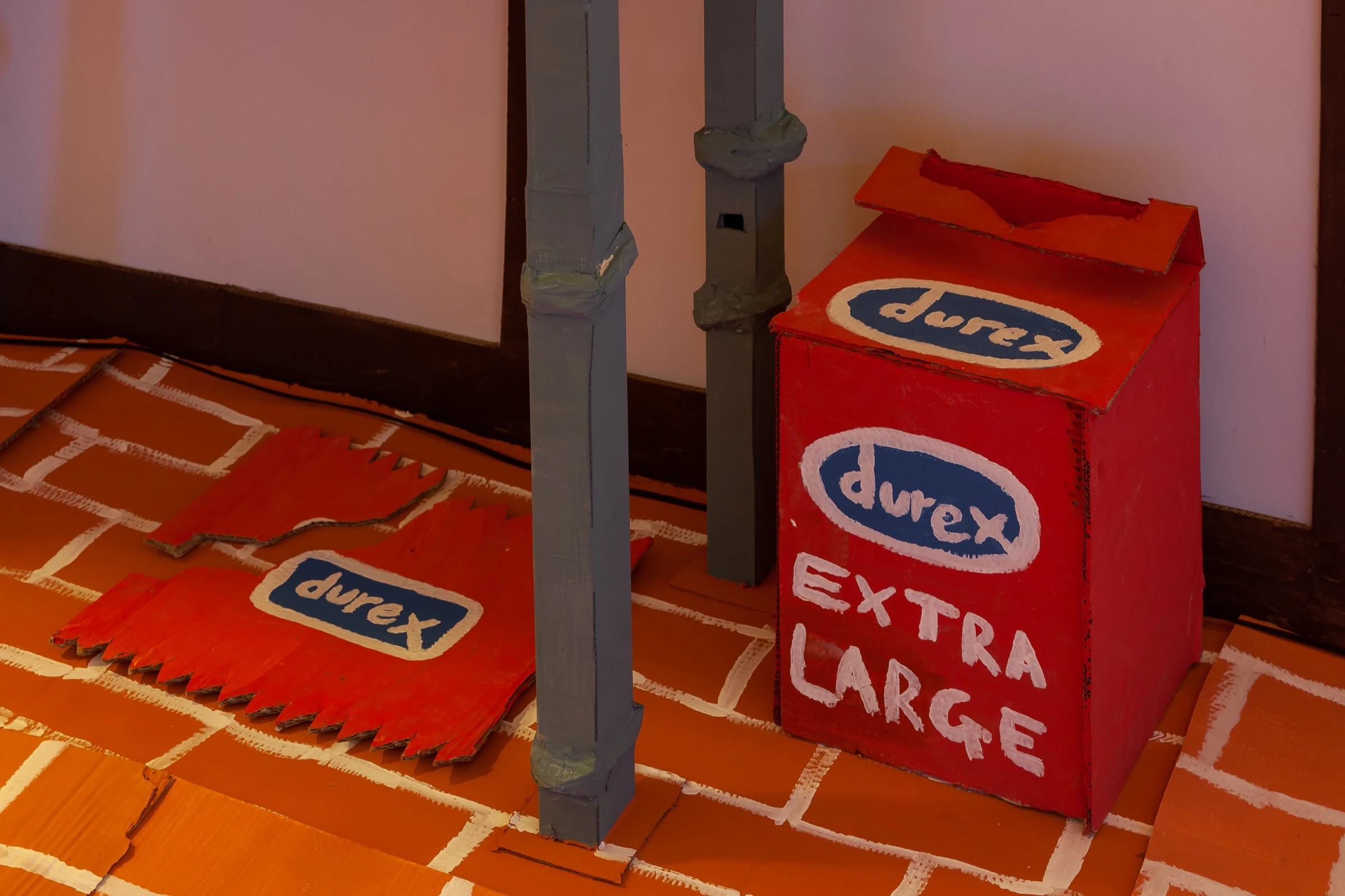 A large red cardboard condom box beneath the kitchen counter.