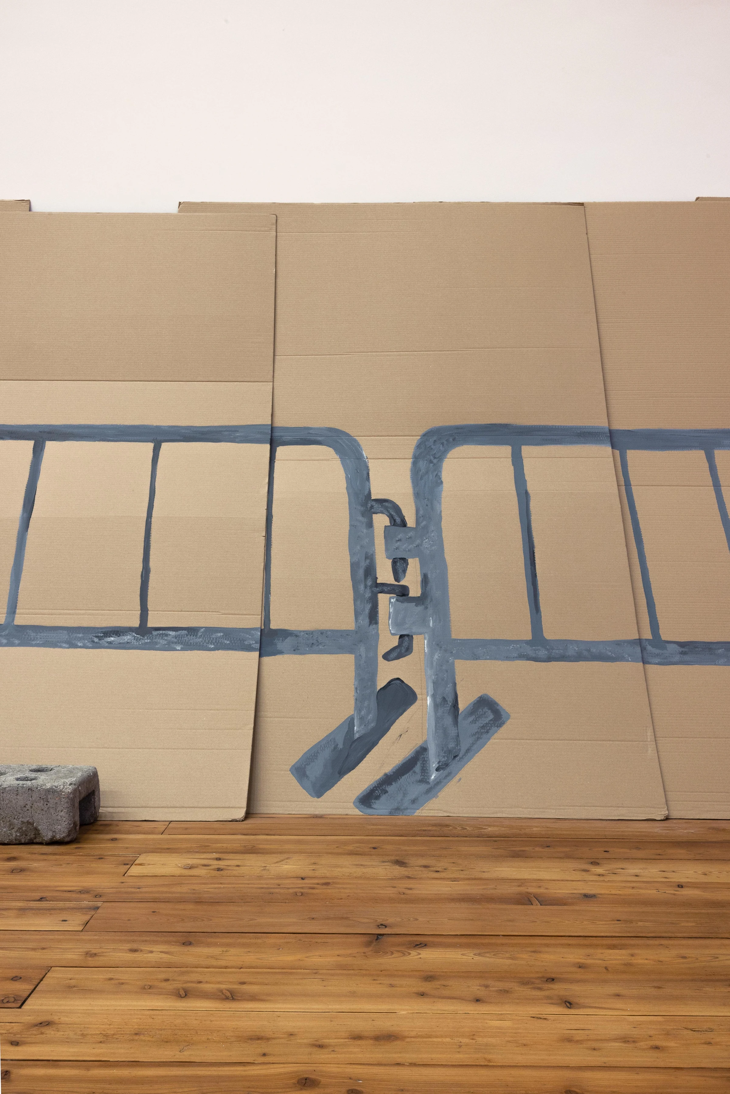 Two blue crowd-control barriers painted on cardboard panels above a wooden floor.
