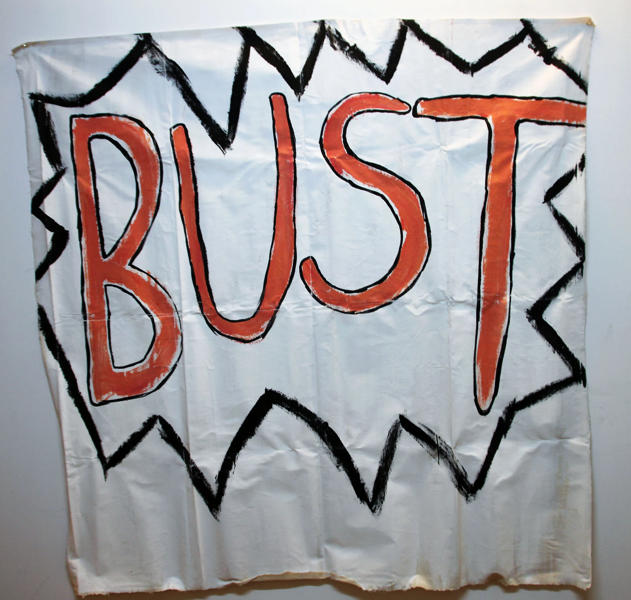 A white canvas backdrop with large orange BUST lettering and a jagged black border.