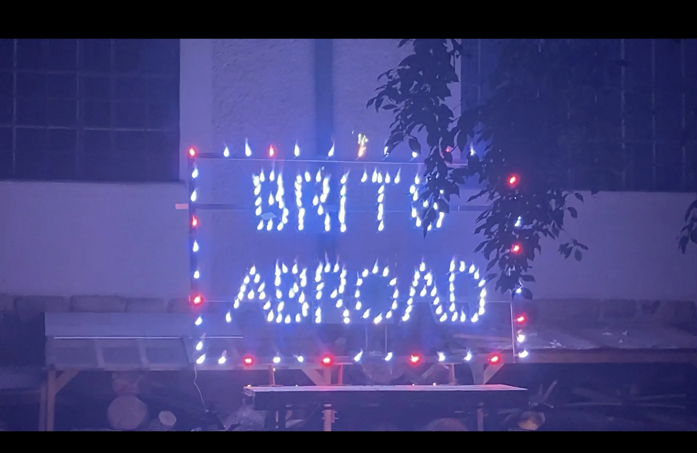An illuminated BRITS ABROAD sign surrounded by blue light and smoke.