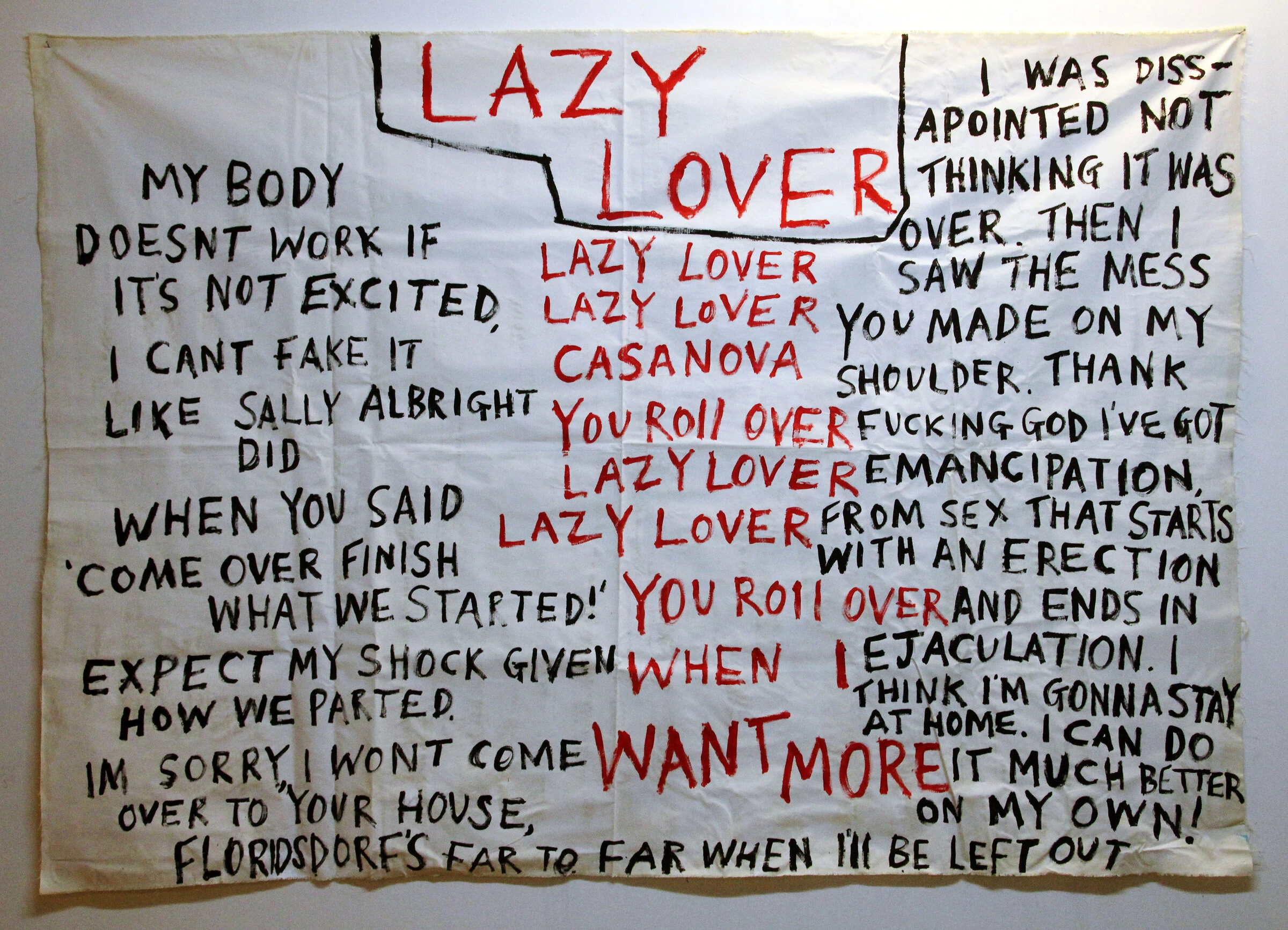 A white canvas backdrop covered in red and black hand-painted text headed Lazy Lover.