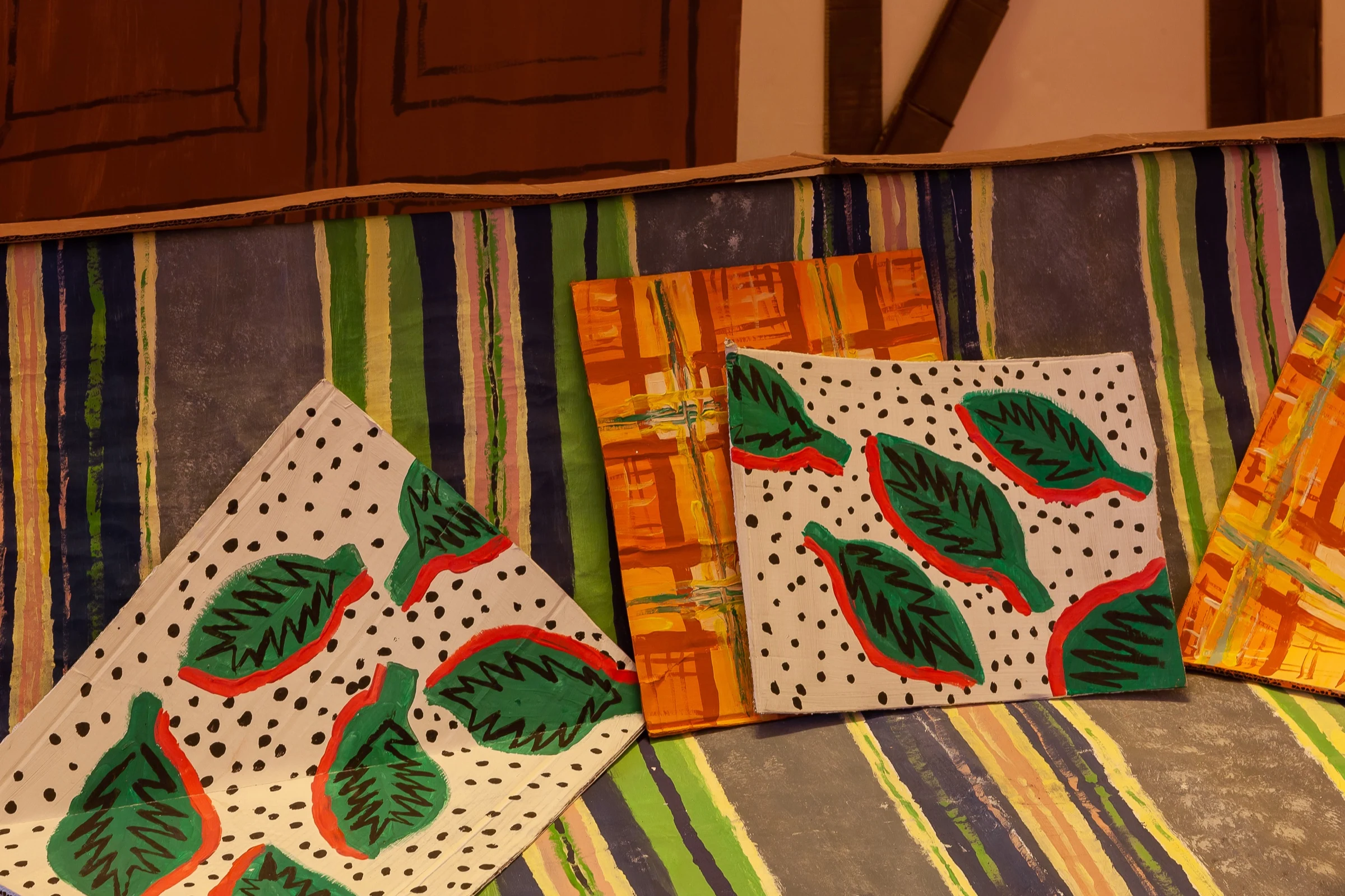 Painted cushions on the striped cardboard sofa.