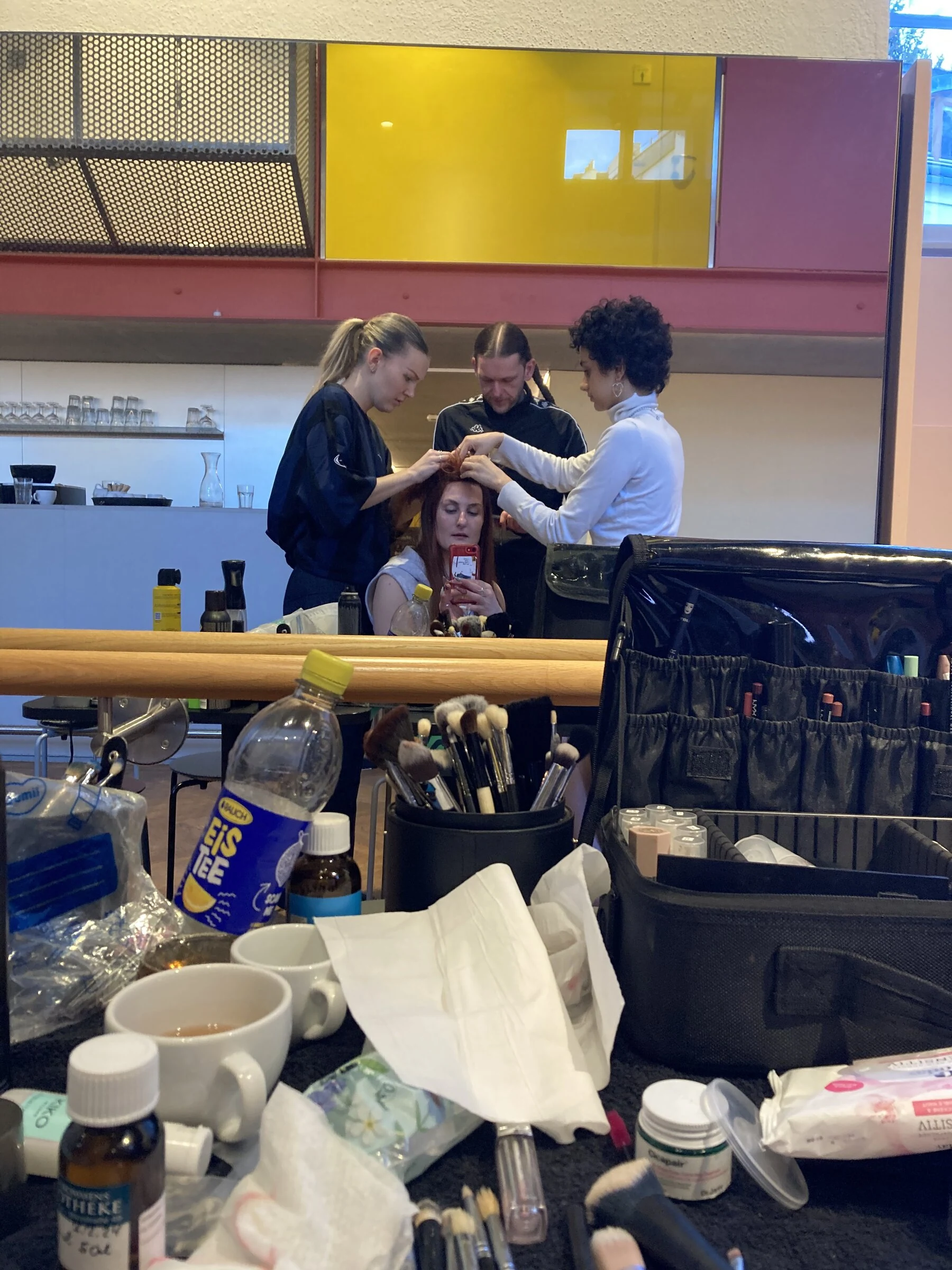 Charlotte having her hair and makeup prepared in front of a mirror for the photo shoot.