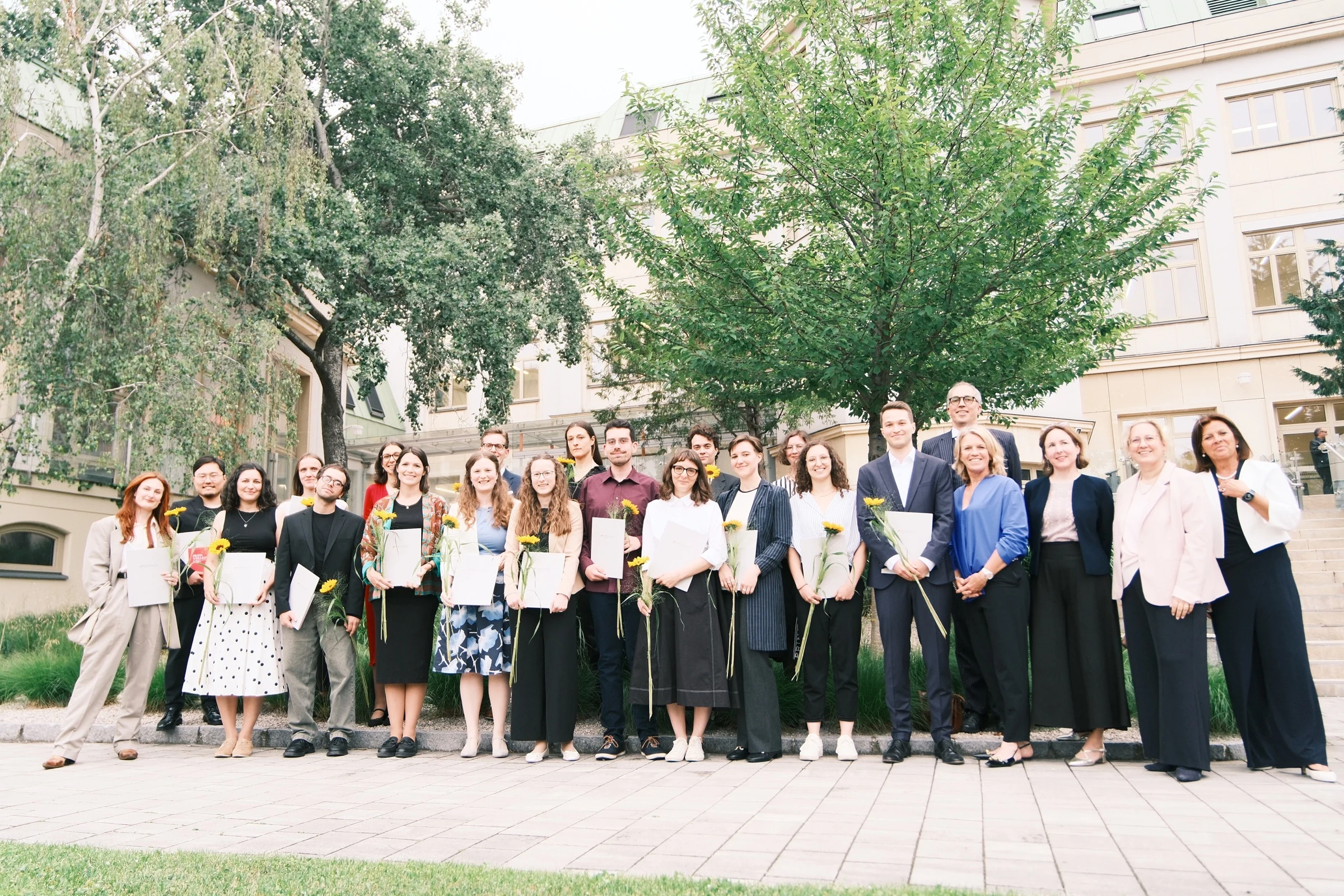 Theodor Körner Prize recipients and ceremony representatives posing outdoors with certificates and sunflowers.