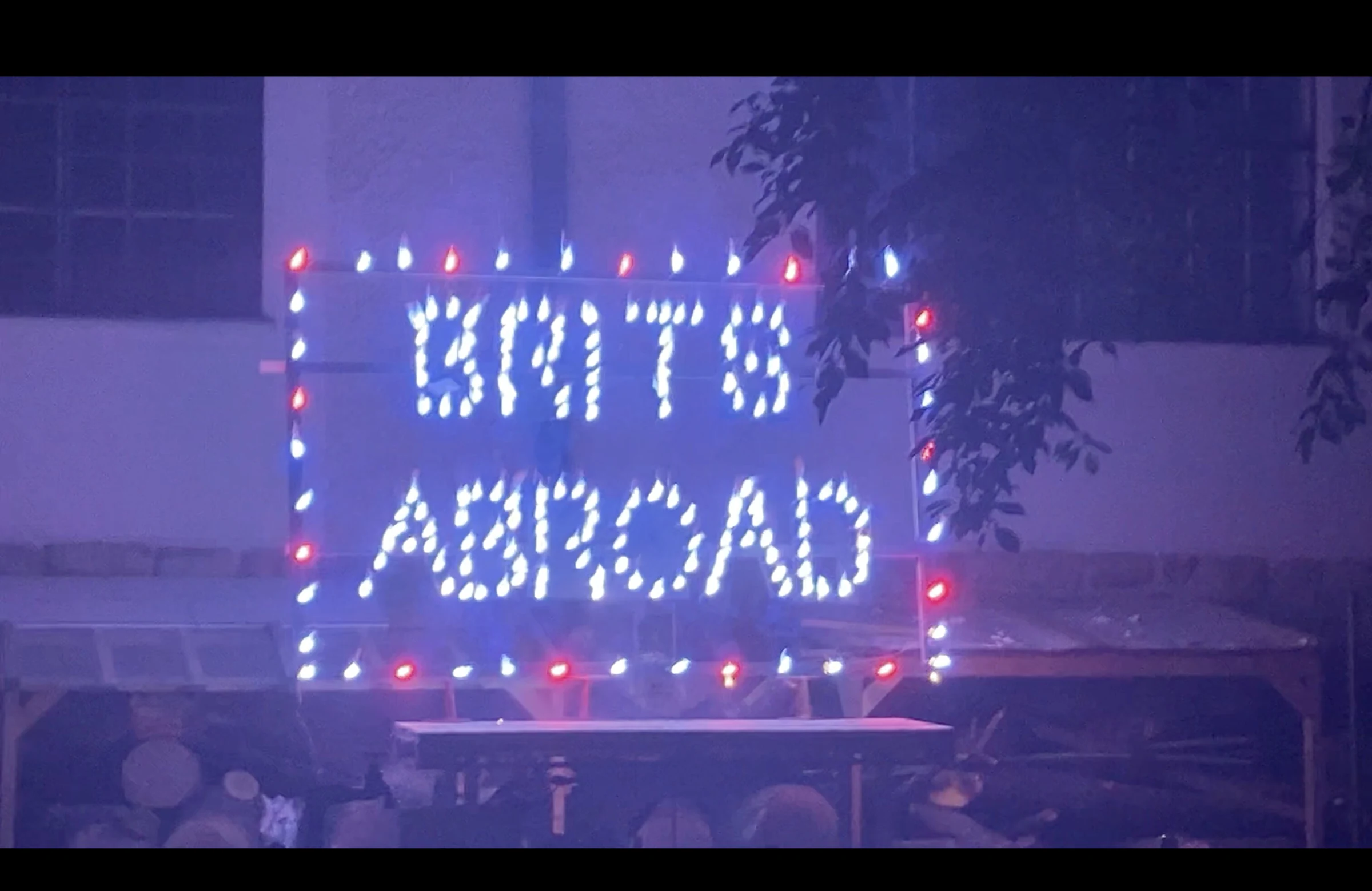 A close view of the BRITS ABROAD sign framed by blue and red lights.
